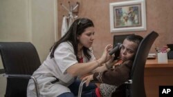 In this Wednesday, July 24, 2019 photo, a nurse performs skin check-ups for 8 year-old Mustapha, who is affected by a rare disorder called xeroderma pigmentosum, or XP, inside a hospital in Casablanca, Morocco. 