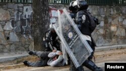 Policías venezolanos reprimen una protesta popular y se llevan detenido a un manifestante.