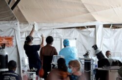 FILE - Health workers attend to patients in tents at the parking lot of the Steve Biko Academic Hospital, amid a nationwide coronavirus disease (COVID-19) lockdown, in Pretoria, South Africa, Jan. 11, 2021.