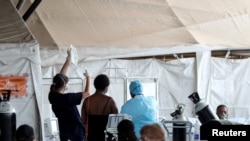 Health workers attend to patients in tents at the parking lot of the Steve Biko Academic Hospital, amid a nationwide coronavirus disease (COVID-19) lockdown, in Pretoria, South Africa, Jan. 11, 2021. 