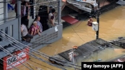 Foto udara menunjukkan warga di rumah mereka yang terendam banjir di kawasan Pasar Minggu, Jakarta, pada 4 Maret 2025. (Foto: AFP/BAY ISMOYO)