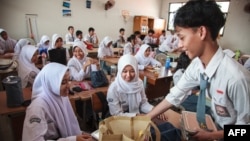 Para siswa menerima kotak makan siang pada hari pertama program makan gratis di SMA Negeri 11, Jakarta Timur, 6 Januari 2025. (Foto: AFP)