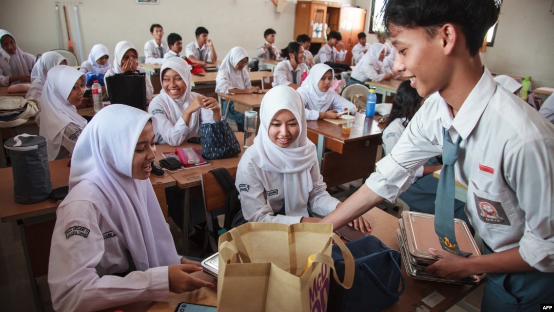 Siswa menerima piring makan siang pada hari pertama program makan gratis di SMA Negeri 11, Jakarta Timur, 6 Januari 2025. (Aditya IRAWAN / AFP)