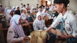 Siswa menerima piring makan siang pada hari pertama program makan gratis di SMA Negeri 11, Jakarta Timur, 6 Januari 2025. (Aditya IRAWAN / AFP)