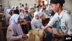 Siswa menerima piring makan siang pada hari pertama program makan gratis di SMA Negeri 11, Jakarta Timur, 6 Januari 2025. (Aditya IRAWAN / AFP)