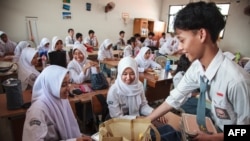 Siswa menerima piring makan siang pada hari pertama program makan bergizi gratis di SMA Negeri 11, Jakarta Timur, pada 6 Januari 2025. (Foto: AFP)