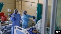 Deux infirmières sont vues à côté d'une machine qui vérifie les niveaux d'oxygène d'un patient A infecté par le COVID-19 au service numéro 20 de l'hôpital Tembisa de Tembisa, le 2 mars 2021 (Photo de Guillem Sartorio / AFP)