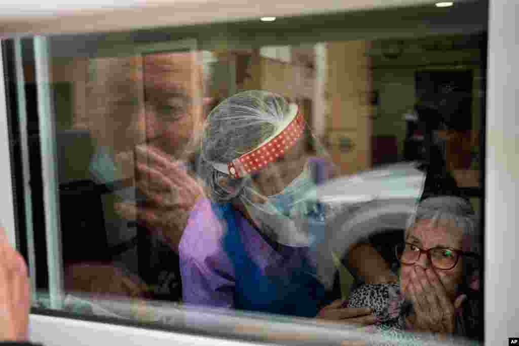 Javier Anto, 90, and his wife Carmen Panzano, 92, blow kisses to one another through the window at a nursing home in Barcelona, Spain.