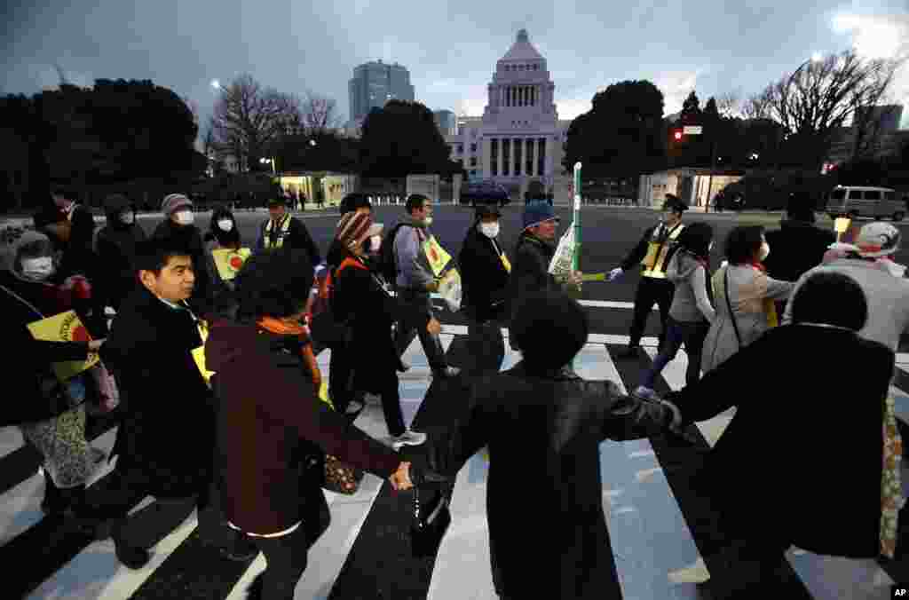 Anti-nuclear protesters form a human chain around the parliament building during a march, in Tokyo, March 11, 2012. (Reuters)
