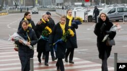 A crew of a Ukrainian airlines carry flowers to pay tribute to the flight crew members of the Ukrainian 737-800 plane that crashed on the outskirts of Tehran, arrive for memorial service at Borispil international airport outside Kyiv, Jan. 19, 2020.