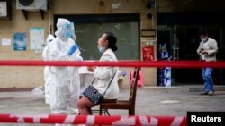 A medical worker in protective suit conducts tests for residents in Wuhan, the Chinese city hit hardest by the coronavirus disease, Hubei province, China, May 15, 2020. A small trial of a coronavirus vaccine in Wuhan showed "unimpressive" results.