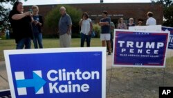 FILE - early voters stand by campaign signs as they wait in line at a voting location in Dallas. 