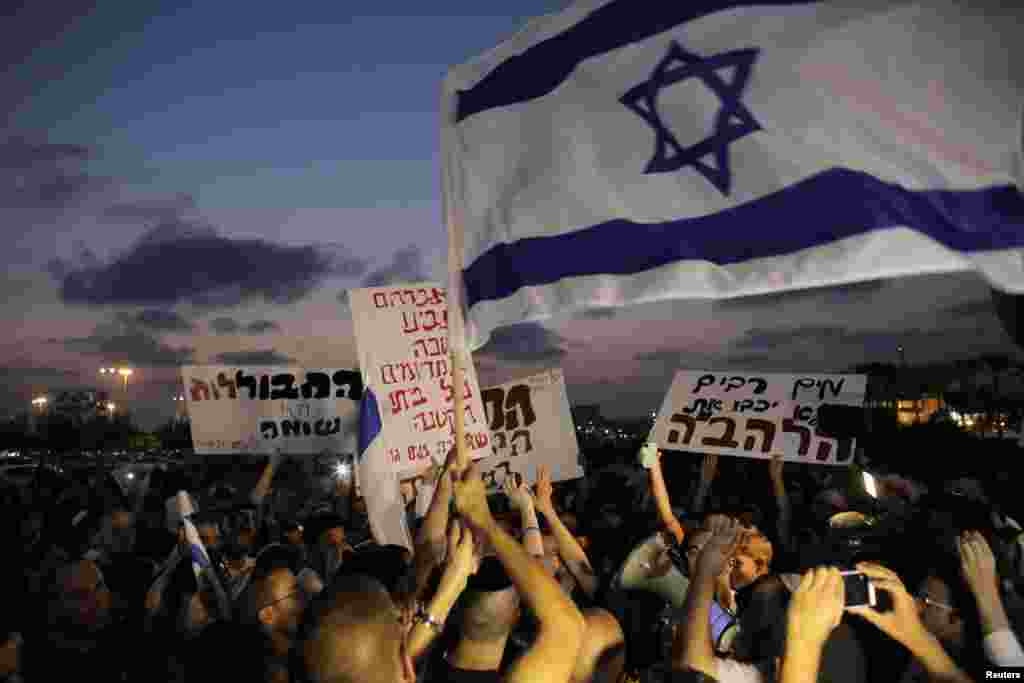 Protesters hold signs and shout slogans against the wedding, near Tel Aviv, Aug. 17, 2014.