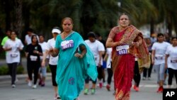 Dua orang perempuan tengah baya mengenakan pakaian tradisional India mengikuti lari lima kilometer untuk memperingati Hari Perempuan Internasional di Banglore, India (8/3). Jaringan televisi India, NDTV, melancarkan protes siaran bisu, setelah pemerintah melarang stasiun televisi itu menayangkan film “India's Daughter”, Minggu malam (8/3). 