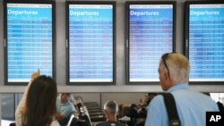 Passengers check arrival and departure displays at O'Hare International Airport in Chicago, Illinois, Sept. 27, 2014.