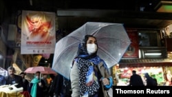 FILE - An Iranian woman wears a protective face mask and gloves, amid fear of coronavirus disease (COVID-19), as she walks at Tajrish market, March 20, 2020, in Tehran