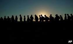 Migranti koji su prešli Rio Grande i ušli u SAD iz Meksika stoje u redu za obradu od strane američke carine i granične zaštite, 23. septembra 023. u Eagle Passu, Texas.