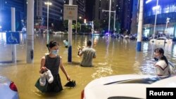 中国安徽合肥的民众在被洪水淹没的街道上过马路。（2020年6月27日）