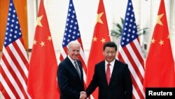 Le président chinois Xi Jinping (à dr.), serrant la main du vice-président américain Joe Biden 