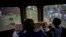 A boy rides next to the engineer of an electric Hershey train in the Casablanca municipality of Havana, Cuba, Aug. 26, 2015.