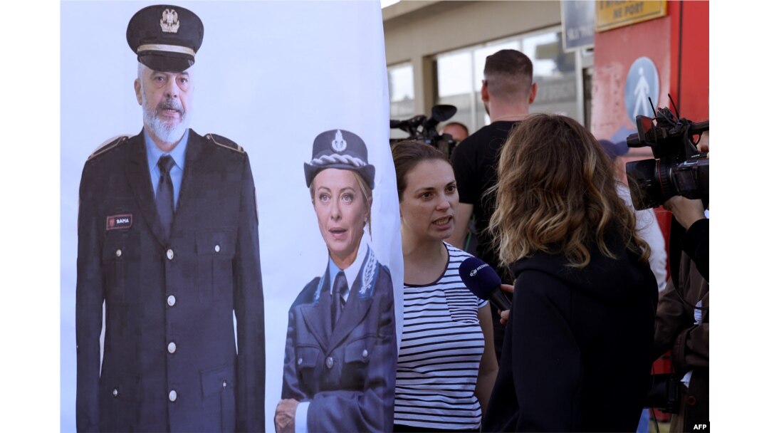 Civil rights activists gather in protest after a group of migrants intercepted in Italian waters arrived at Shengjin port in Albania on Oct. 16, 2024. The banner depicts the prime ministers of Albania, Edi Rama, and Italy, Giorgia Meloni.