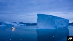 FILE - A boat navigates at night next to large icebergs in eastern Greenland, Aug. 5, 2019.