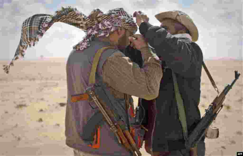 Libyan rebels try to cover themselves from the wind on the frontline of the outskirts of the city of Ajdabiya, south of Benghazi, eastern Libya, Monday, March 21, 2011. The international military intervention in Libya is likely to last "a while," a top Fr