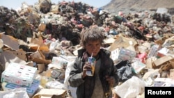 Un enfant boit un jus périmé sur une décharge à Sanaa, au Yémen.