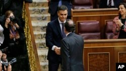 El presidente del gobierno español Mariano Rajoy (derecha) saluda al líder socialista Pedro Sánchez, después del voto de no confianza en el parlamento en Madrid el viernes, 1 de junio, de 2018.