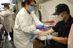 Jersey City firefighter Matt Finnerty, right, has blood drawn to test for coronavirus antibodies at a testing site in Jersey City, New Jersey, May 4, 2020.