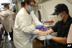 Jersey City firefighter Matt Finnerty, right, has blood drawn to test for coronavirus antibodies at a testing site in Jersey City, New Jersey, May 4, 2020.
