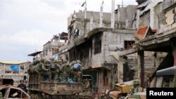 Truk militer yang penuh dengan tentara pemerintah melewati rumah-rumah dan gedung-gedung yang rusak sementara para tentara terus melakukan operasi menentang militan yang pro-ISIS yang merebut distrik Mapandi di Marawi city, Filipina selatan, 13 September.