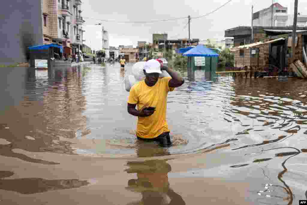 A man carries his belongings out of his house in the flooded neighbourhood of Keur Massar, Dakar.