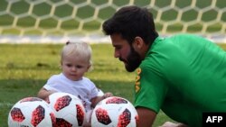 Alisson Becker, kiper timnas Brazil, bermain dengan anak perempuannya Helena saat sesi latihan di Stadion Yug Sport di Sochi, 3 Juli 2018, menjelang laga perempat final Piala Dunia 2018 antara Brazil dan Belgia.