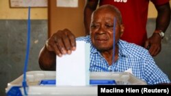 Un électeur dépose son bulletin de vote dans un bureau de vote lors des élections législatives à Abidjan, Côte d'Ivoire, le 6 mars 2021.