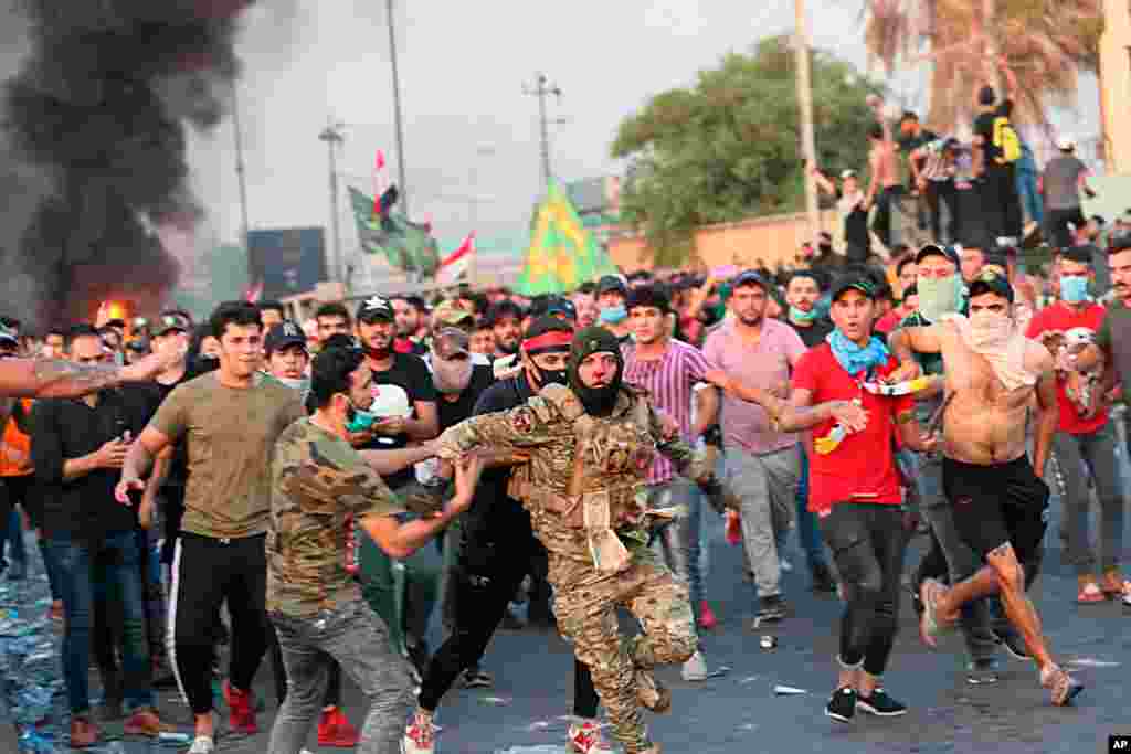 Anti-government protesters help a soldier with the Federal Police Rapid Response Forces get out of the area after other protesters beat him, in Baghdad, Iraq, Oct. 3, 2019.