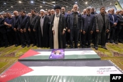 Pemimpin tertinggi Iran Ayatollah Ali Khamenei memimpin salat jenazah bersama Presiden Iran Masoud Pezeshkian (tengah-kanan) di atas peti jenazah mendiang pemimpin Hamas Ismail Haniyeh dan pengawalnya. (Foto: AFP)