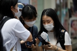 FILE - Students wearing masks look at a mobile phone amid the coronavirus disease (COVID-19) pandemic in Seoul, South Korea, Aug. 25, 2020.