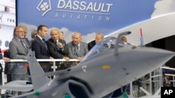 French President Emmanuel Macron, second left, listens to Dassault Aviation CEO Eric Trappier, center, while visiting the Paris Air Show in Le Bourget, north of Paris, June 19, 2017. 