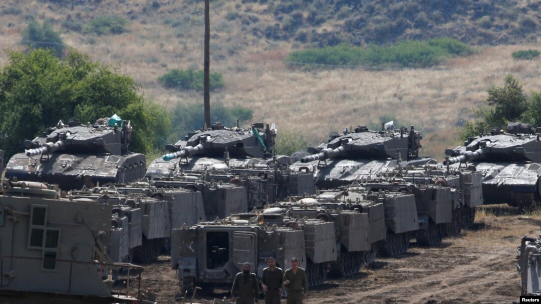 Tentara Israel berjalan di antara kendaraan lapis baja di Dataran Tinggi Golan yang diduduki Israel, 10 Mei 2018. 