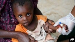 FILE - A little boy is held by his mother and a nurse as he receives treatment for cholera at the small and overwhelmed health clinic in Anse d'Hainault, southwestern Haiti, Oct. 14, 2016. 