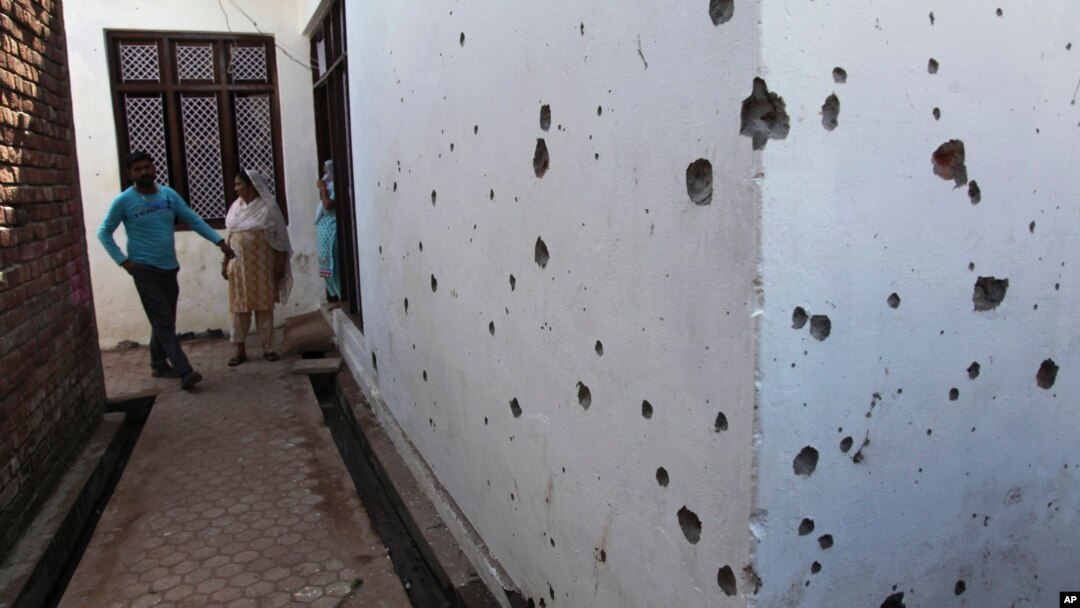  FILE - Indian villagers look at one of the houses damaged in firing by Pakistani troops at Village Nanga, in the Ramgarh sector of Jammu and Kashmir state, India, Oct. 9, 2014.