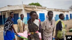 Women carry the body of a civilian killed in the center of Malakal, Upper Nile State in South Sudan, Jan. 21, 2014. The town erupted in violence again Tuesday.