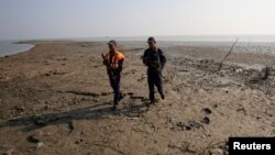 Bangladesh coast guards walk in the Thengar Char island in the Bay of Bengal, Bangladesh, Feb. 2, 2017.