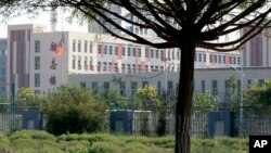 FILE - Barbed wire protects the walls around a cluster of schools on the outskirts of Kashgar, in western China's Xinjiang region, Aug. 31, 2018.