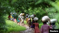 FILE - Flood victims from Mtauchira village carry food they received from the Malawi government in the aftermath of Cyclone Freddy that destroyed their homes in Blantyre, Malawi, March 16, 2023.