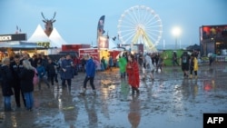 Visitors to the music festival Rock am Ring are seen wading through mud after a heavy downpour in the west German city of Mendig, June 3, 2016. Organizers canceled the final day of the three-day event after lightning strikes injured at least 72 fans. 