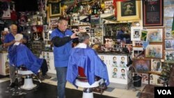 Bennie Botes (far left) and Louis de Hart at work inside their barbershop in Newlands, Johannesburg. The wall holds just a fraction of the rugby memorabilia collected by Botes over the past 50 years. (Darren Taylor for VOA News)