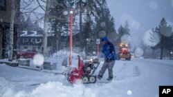 This photo provided by Mammoth Lakes Tourism shows snow being cleared along the street in the Town of Mammoth Lake, Calif., during heavy snowfall on Dec. 9, 2021.