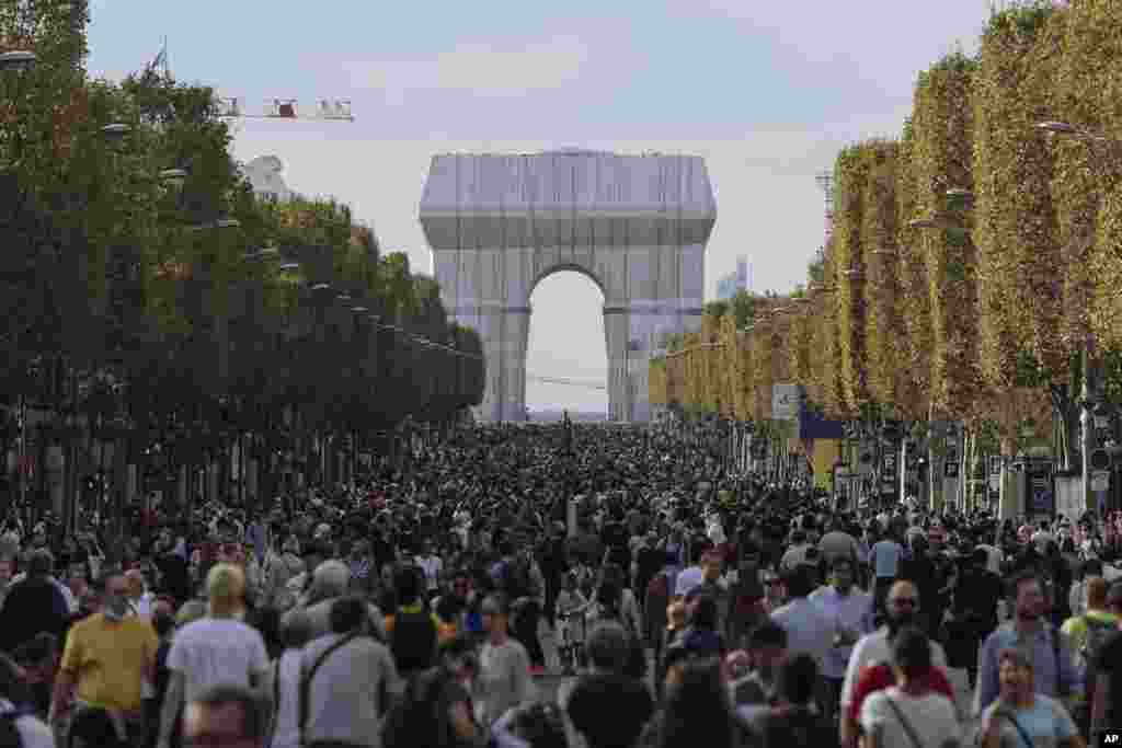 People walk along the Champs Elysees Avenue, Paris, during the &quot;day without cars&quot;, with the Arc de Triomphe in the background.